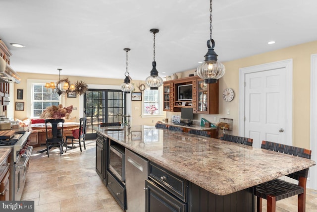 kitchen with stainless steel appliances, a kitchen bar, decorative light fixtures, and a kitchen island