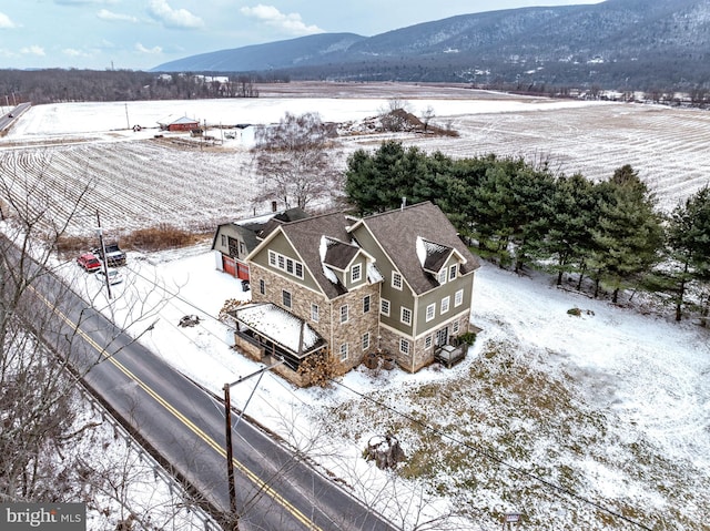 snowy aerial view featuring a mountain view and a rural view