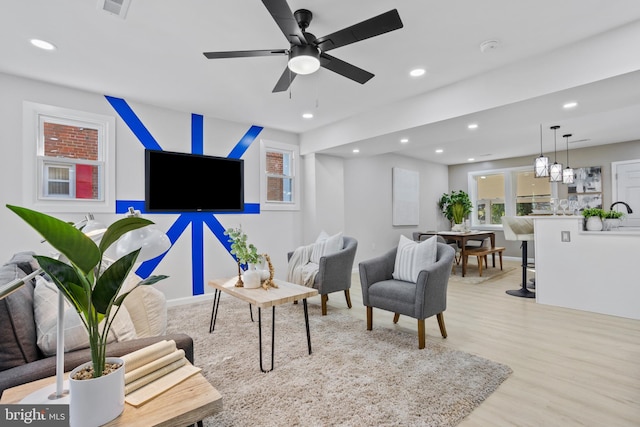 living room with light hardwood / wood-style floors and ceiling fan