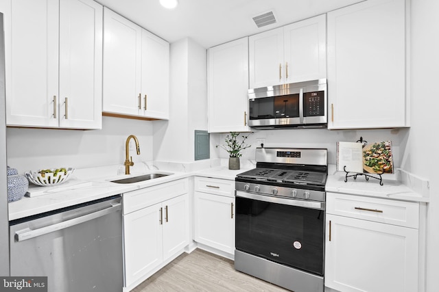 kitchen featuring sink, stainless steel appliances, white cabinets, and light stone countertops