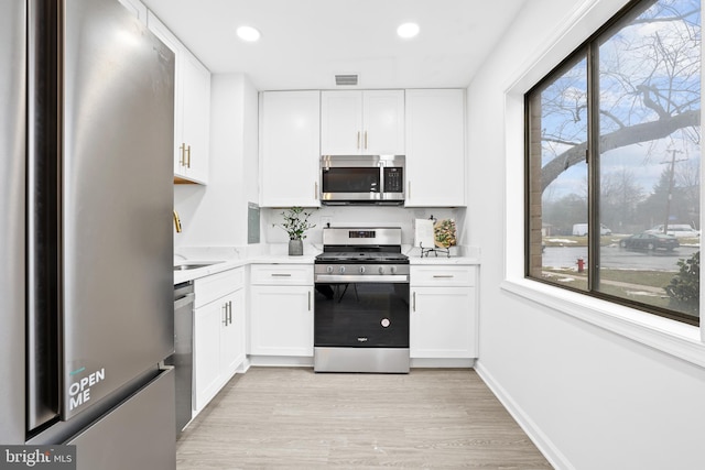 kitchen featuring white cabinetry, stainless steel appliances, sink, and light wood-type flooring