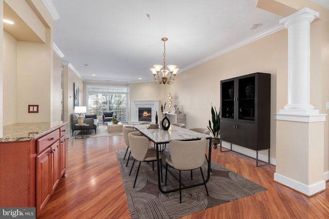 dining area with decorative columns, a chandelier, ornamental molding, and hardwood / wood-style floors