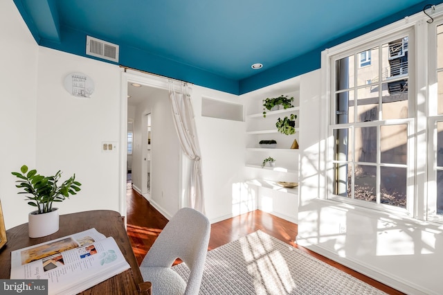 office space with built in shelves and hardwood / wood-style floors