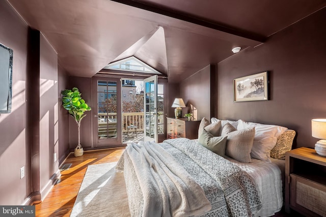 bedroom with access to exterior, vaulted ceiling, and light hardwood / wood-style flooring