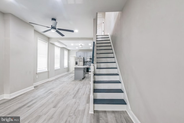 stairs with hardwood / wood-style flooring and ceiling fan