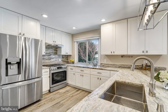 kitchen featuring sink, white cabinets, light hardwood / wood-style floors, stainless steel appliances, and light stone countertops