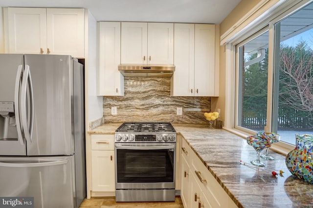 kitchen featuring light stone countertops, white cabinetry, appliances with stainless steel finishes, and tasteful backsplash