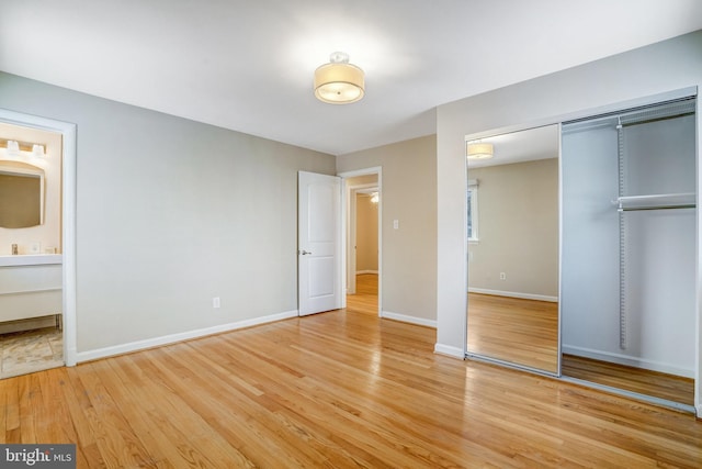 unfurnished bedroom featuring light hardwood / wood-style flooring, a closet, and ensuite bathroom