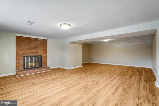 unfurnished living room with a brick fireplace and light hardwood / wood-style flooring