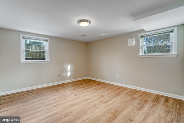 basement featuring a healthy amount of sunlight and light hardwood / wood-style floors