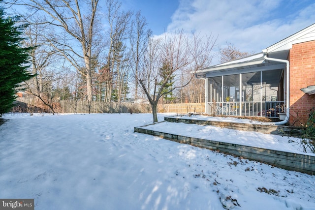 snowy yard featuring a sunroom