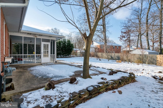 yard covered in snow featuring a sunroom