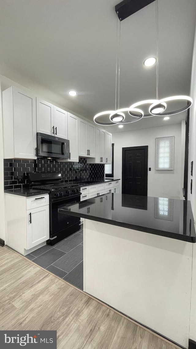 kitchen featuring black appliances, white cabinets, pendant lighting, and dark hardwood / wood-style floors