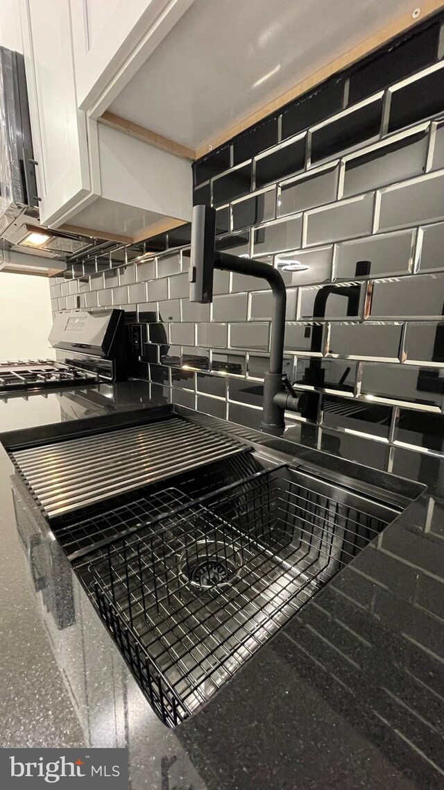 room details featuring white cabinets, gas range, and tasteful backsplash