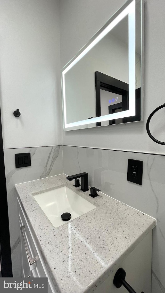 bathroom with vanity, backsplash, and tile walls