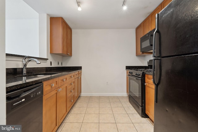 kitchen with dark stone counters, sink, rail lighting, and black appliances