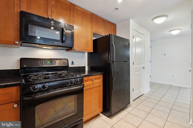 kitchen featuring black appliances, dark stone countertops, and light tile patterned floors