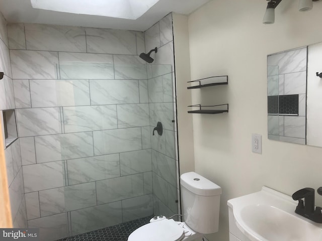 bathroom with toilet, a tile shower, and sink