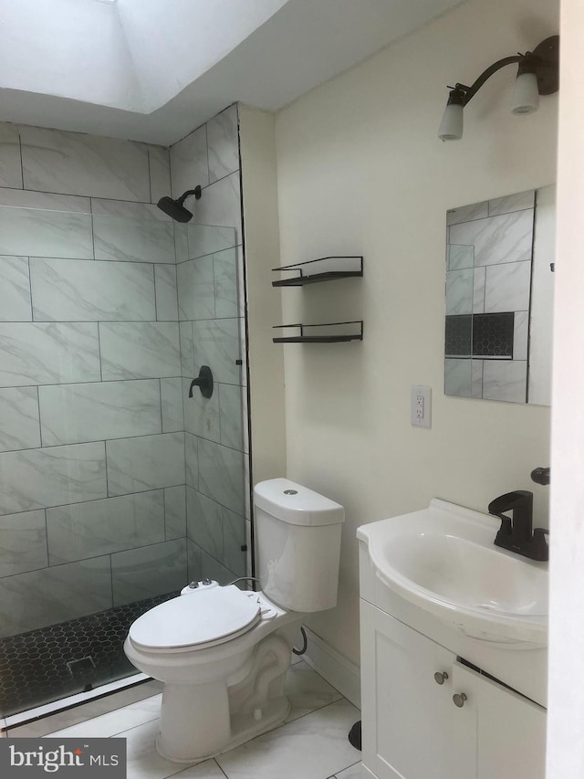 bathroom with a tile shower, vanity, and toilet