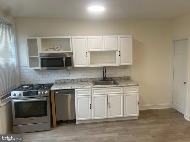 kitchen featuring decorative backsplash, stainless steel appliances, white cabinetry, and sink