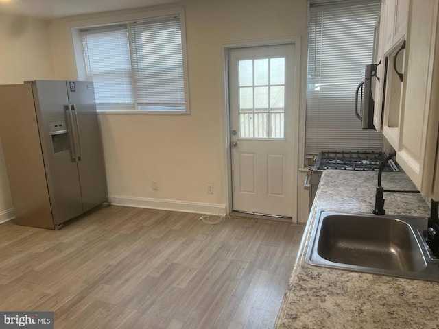 kitchen with stainless steel refrigerator with ice dispenser, light hardwood / wood-style floors, and sink