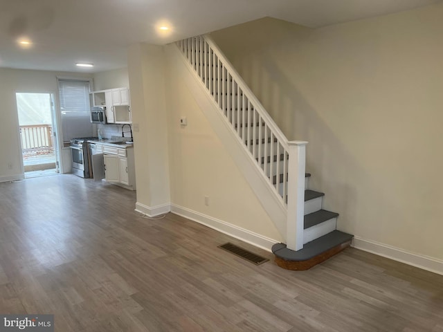 staircase with sink and wood-type flooring