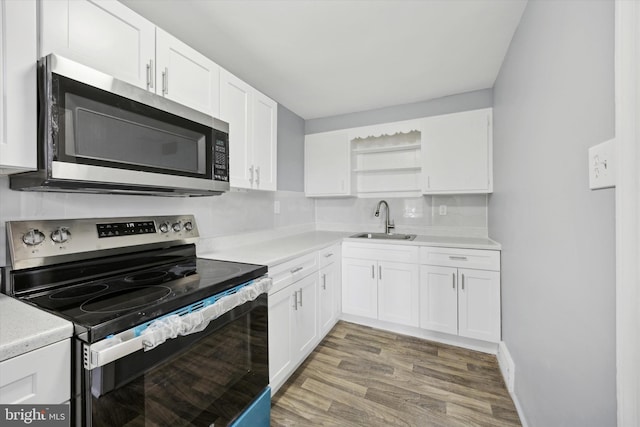 kitchen featuring backsplash, sink, appliances with stainless steel finishes, white cabinetry, and wood-type flooring