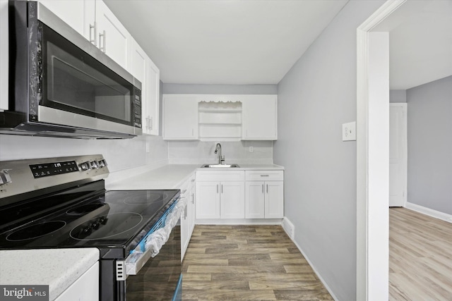 kitchen with light wood-type flooring, white cabinetry, sink, and appliances with stainless steel finishes