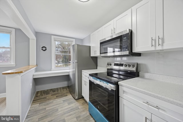 kitchen featuring a wealth of natural light, white cabinetry, stainless steel appliances, and light wood-type flooring