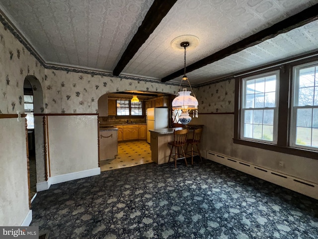 dining area with beamed ceiling and a baseboard heating unit