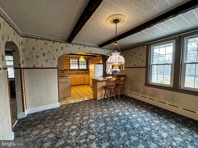 dining space with beam ceiling and a baseboard radiator