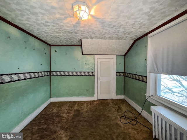 unfurnished room featuring carpet flooring, radiator, and vaulted ceiling