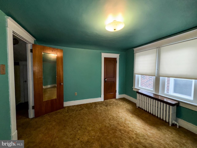 unfurnished bedroom with radiator, a closet, and carpet floors