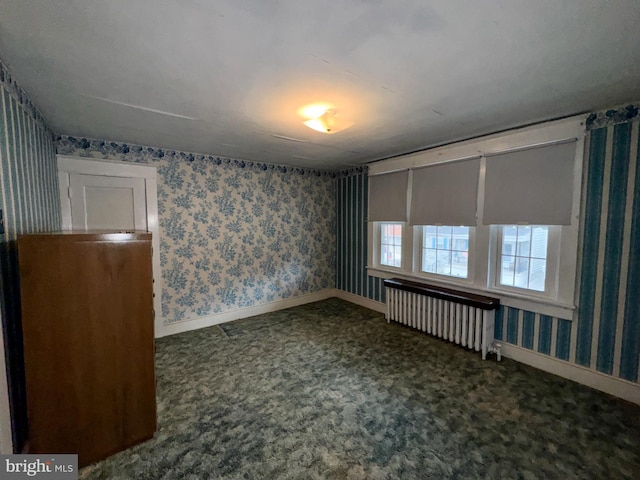 empty room featuring radiator heating unit and dark carpet