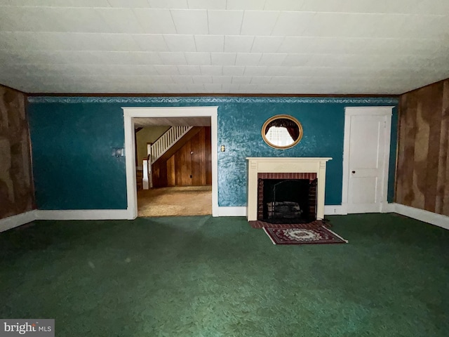 unfurnished living room with carpet floors, a brick fireplace, and wooden walls