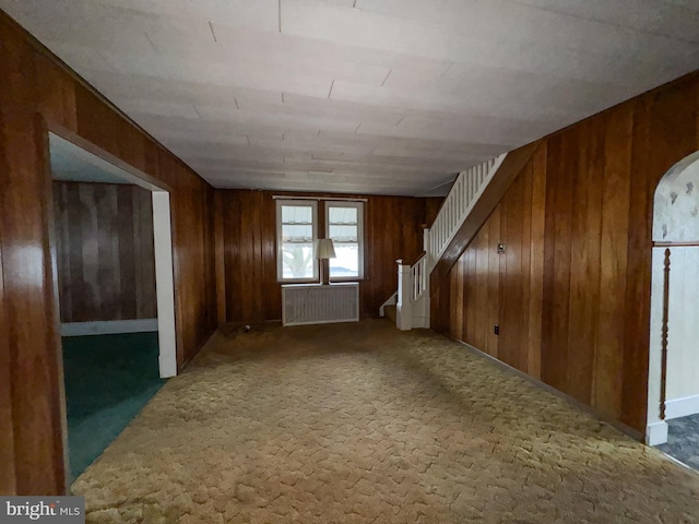 interior space with carpet flooring, wood walls, and radiator