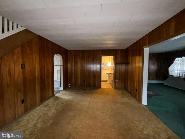 carpeted spare room with wooden walls