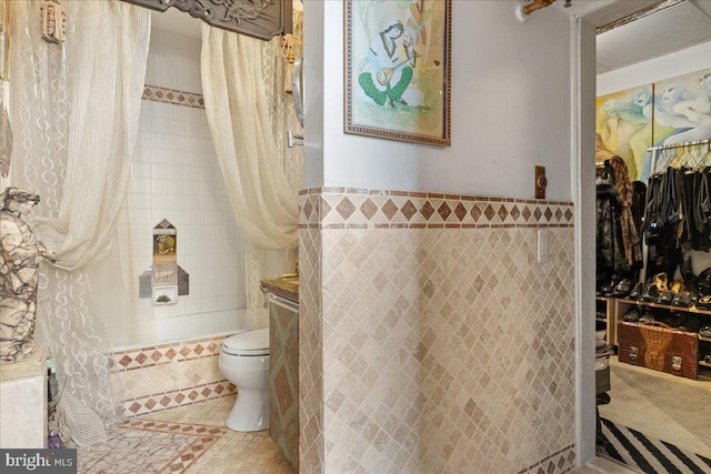 bathroom featuring toilet, tile walls, and shower / tub combo with curtain