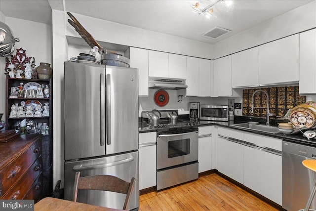 kitchen featuring appliances with stainless steel finishes, light hardwood / wood-style floors, white cabinetry, and sink