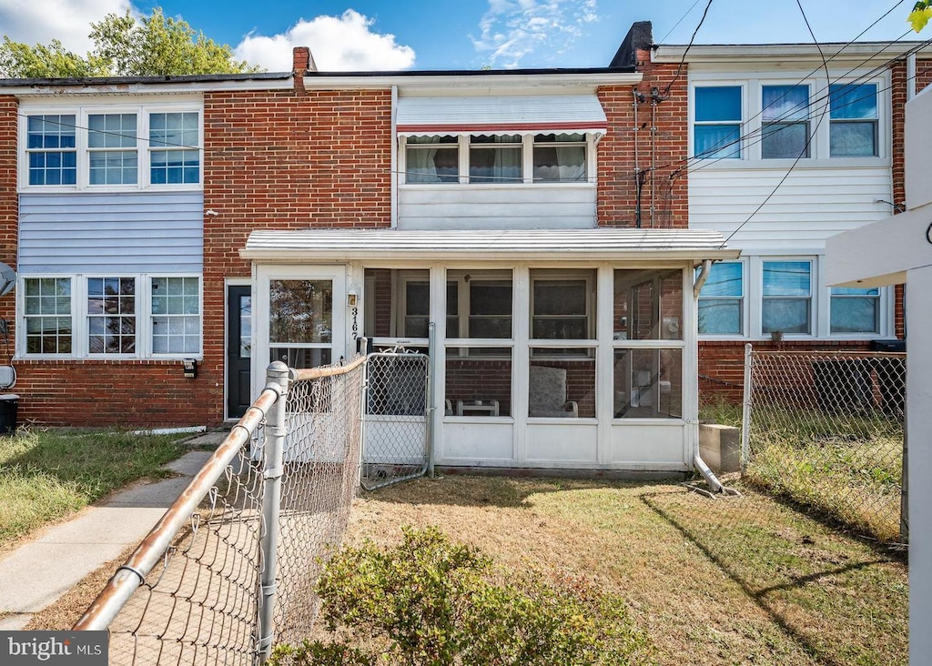 townhome / multi-family property featuring a front yard and a sunroom