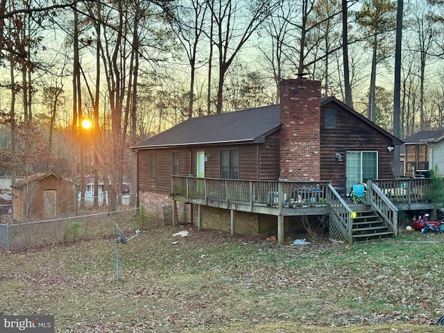 rear view of property featuring fence, a chimney, and a wooden deck