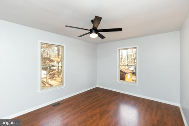 empty room with visible vents, baseboards, dark wood-style floors, and a ceiling fan