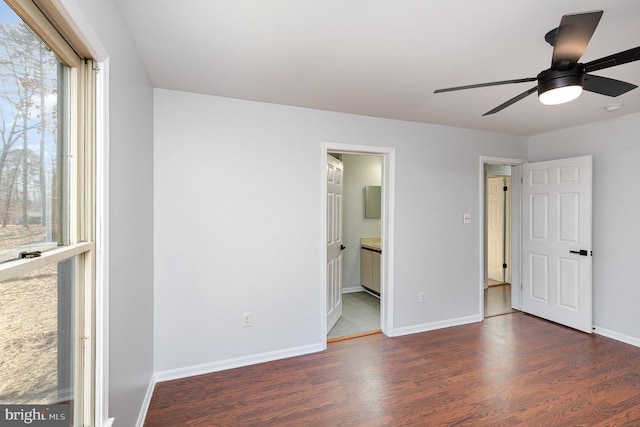 unfurnished bedroom featuring a ceiling fan, wood finished floors, baseboards, and connected bathroom