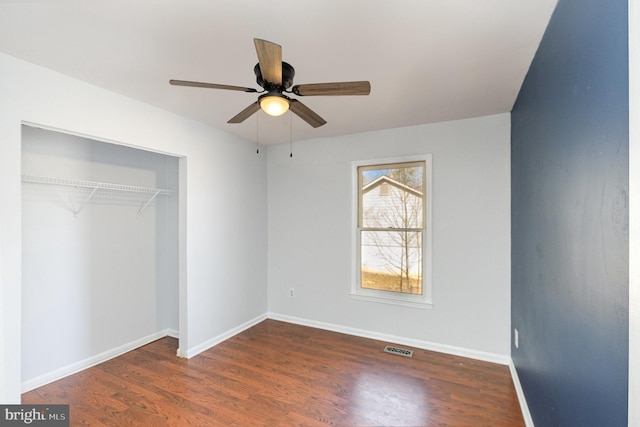 unfurnished bedroom featuring visible vents, a ceiling fan, wood finished floors, a closet, and baseboards