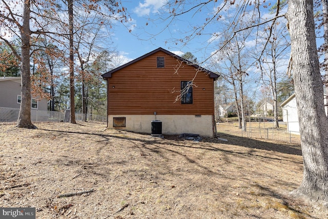 view of side of home with central AC unit and fence