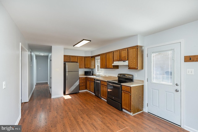 kitchen featuring brown cabinetry, stainless steel appliances, light countertops, and a sink