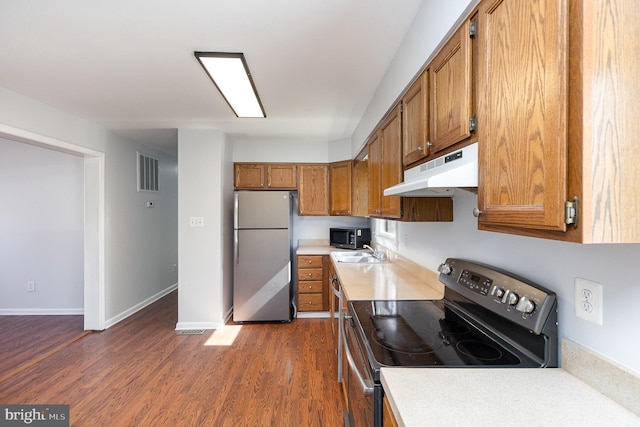 kitchen with visible vents, under cabinet range hood, brown cabinetry, stainless steel appliances, and a sink