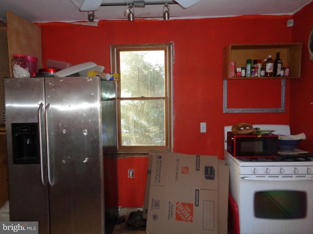 kitchen featuring track lighting, white range with gas stovetop, and stainless steel fridge