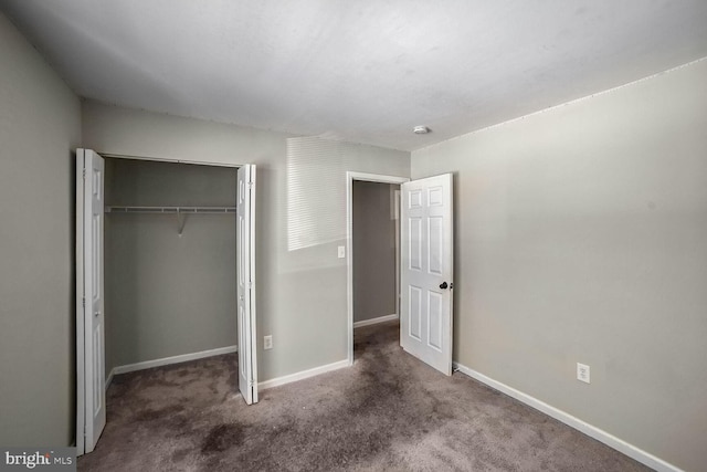 unfurnished bedroom with dark carpet and a closet