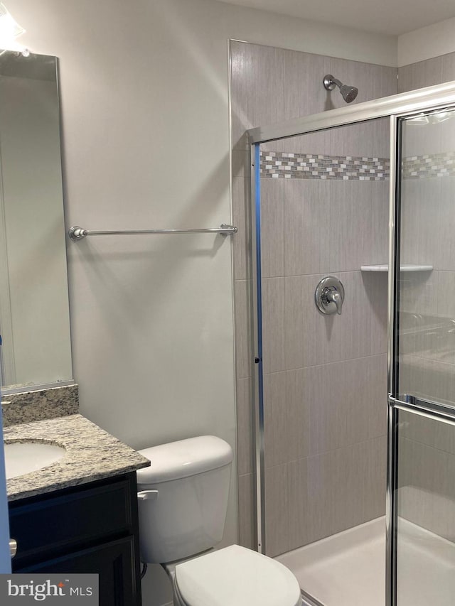 bathroom with vanity, toilet, and a shower with door